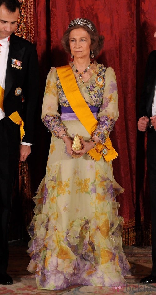 Look de la reina Sofía con vestido de gala largo en color amarillo pastel con llamativos detalles florales en tonos morados y amarillo intenso