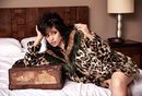 Camila Cabello tumbada sobre la cama con un abrigo de la colección 'Jeans vacaciones 2017' de Guess