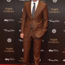 Robert Pattison vistiendo un traje marrón con corbata gris
