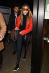 Gigi Hadid con una bomber roja y unos leggings negros saliendo del aeropuerto