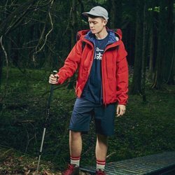 Modelo con un pantalón corto azul y un abrigo rojo de la nueva línea de Outdoor de la nueva colección SS19 de Woolrich