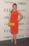 Abigail Breslin con un modelo en naranja y salones beige