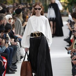 Modelo con una blusa blanca y una falda negra de la colección primavera/verano 2019 de Valentino presentada en Paris Fashion Week