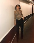 La actriz Zendaya posando con pantalón pinzas negro y blusa cuadros