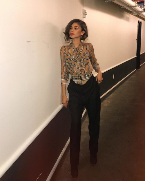 La actriz Zendaya posando con pantalón pinzas negro y blusa cuadros