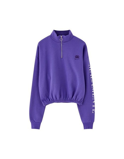 Sudadera violeta con mensaje 'Malamente' en el brazo de la colección cápsula de Rosalía para Pull and Bear