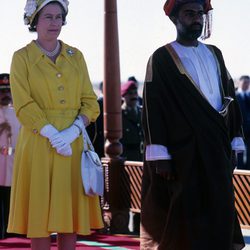 La Reina Isabel II con vestido lady amarillo y sombrero de flores