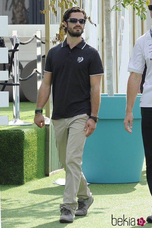 Carlos Felipe de Suecia con un polo azul oscuro, pantalones chinos beige y gafas de sol deportivas