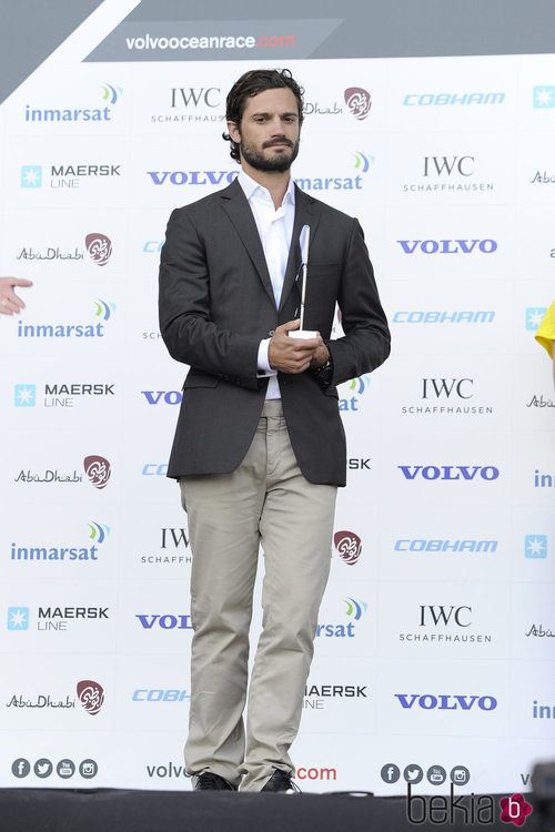 Carlos Felipe de Suecia con americana gris, camisa blanca y pantalones chinos en blanco roto