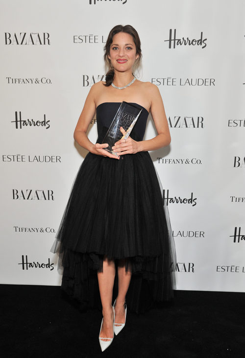 Marion Cotillard con vestido negro sujetando premio a la mujer del año de Harper