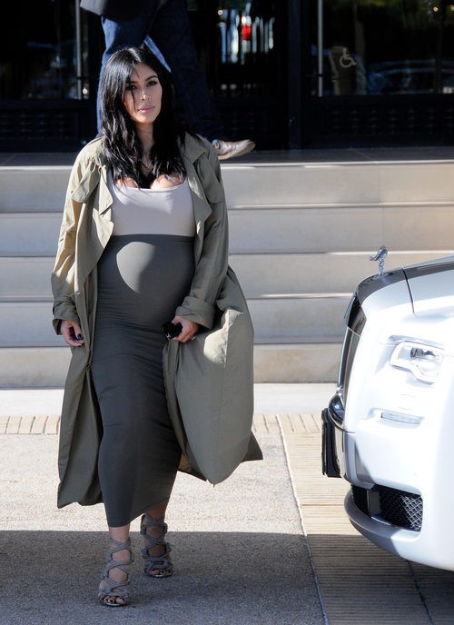 Kim Kardashian con vestido blanco y gris y gabardina larga en su segundo embarazo