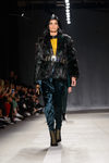 Modelo con abrigo negro y pantalón azulado en el desfile de Balmain para H&M en Nueva York