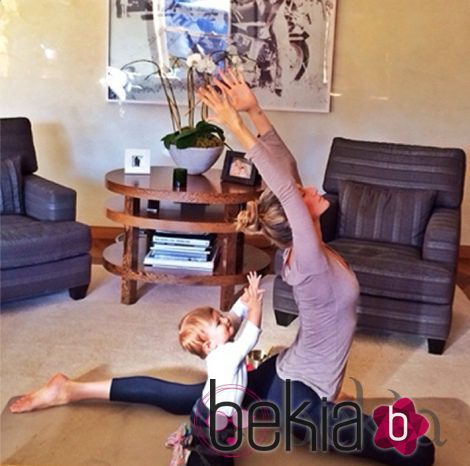 Gisele Bündchen con mallas azul marino y camiseta lila haciendo yoga con su hija Vivian