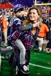 Gisele Bundchen con camisa de cuadros y vaqueros en un partido de la Super Bowl con su hijo