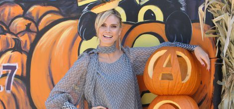 Heidi Klum con blusón y vaqueros junto a una calabaza gigante