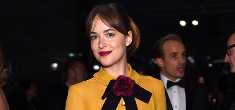 Dakota Johnson con vestido mostaza con lazada burdeos al cuello de la colección Crucero 2016 