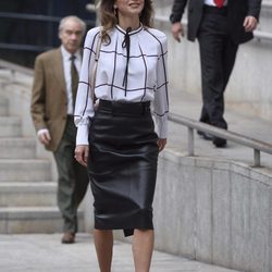 Rania de Jordania con falda de tubo midi en cuero negro y blusón con lazada al cuello  en  su visita al centro cultural Medio-lab prado