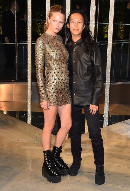 Anna Ewer junto a Alexander Wang con mini vestido ajustado en dorado y botas militares negras