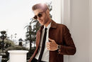 Jon Kortajarena con gafas de sol y traje sastre marrón y ella con vestido de volantes a rayas de Salvatore Ferragamo para la colección 'The Splendor of Lif