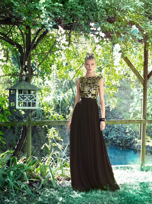 Vestido negro con motivos vegetales dorados en el cuerpo y falda plisada de vuelo de Carla Ruiz