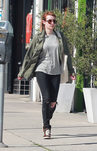 Emma Roberts con abrigo verde militar, pantalón roto y camisa a rayas